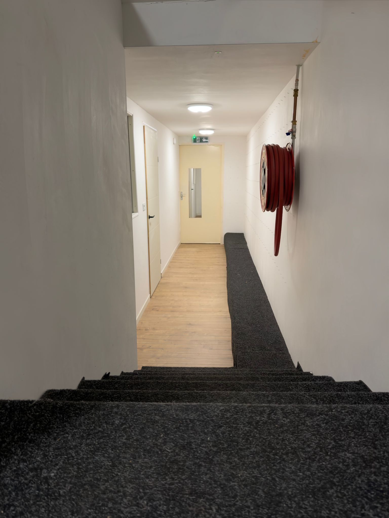 Gang met trap, nooduitgang en brandslanghaspel